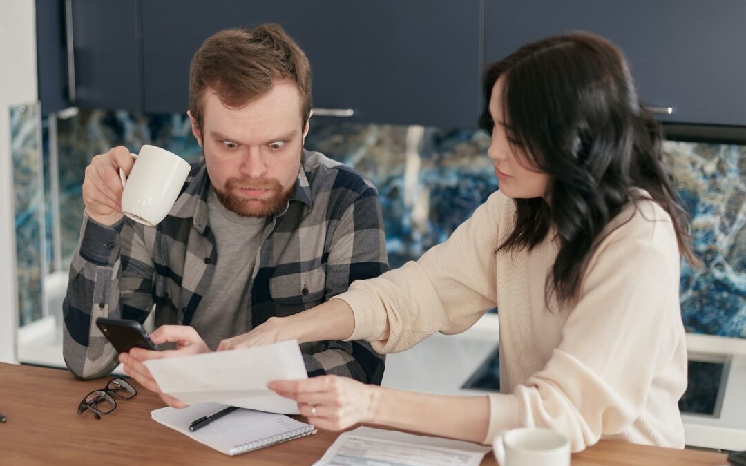 A man looks with consternation at a document that a woman holds out to him.