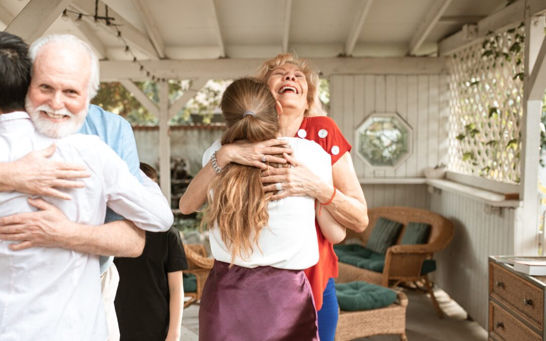 A senior couple hugging their children.